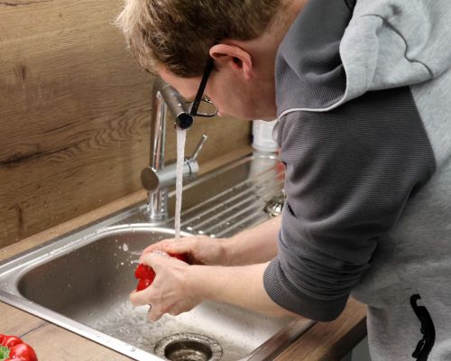 Kursteilnehmer Mark Laufer säubert Paprika unter fließendem Wasser