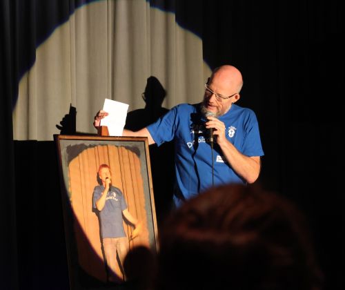 Moderator Joachim Graf mit einem Bild von Theaterfestival-Mitgründer Alexander Hahn