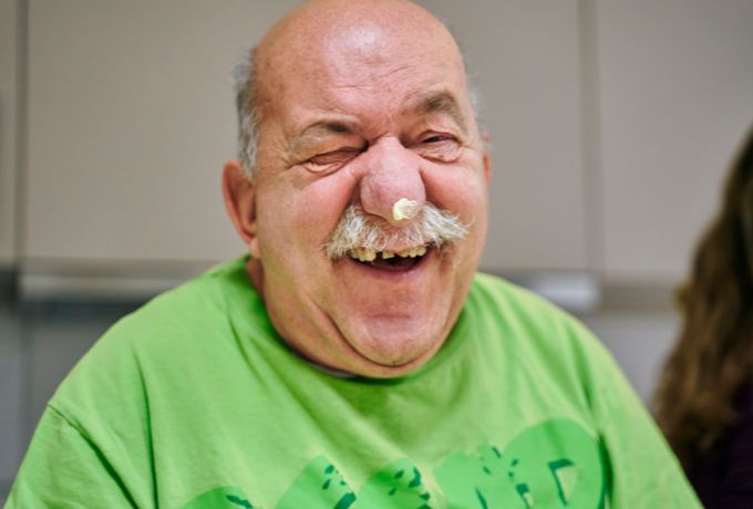 Älterer Mann hat beim Backen in der Tages-Betreuung gute Laune